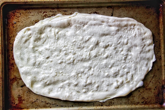 Pizza dough rolled on baking pan.
