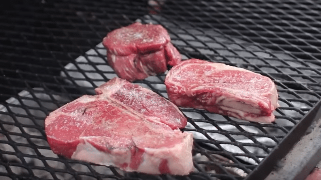 Raw steaks on grill.