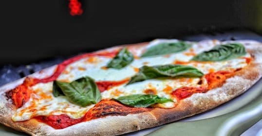 A pizza sitting on top of a grill, making it perfect for restaurant-quality pizza.