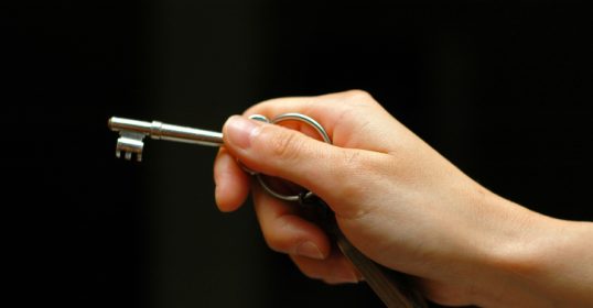 A person's hand holding a key, symbolizing personal agency.