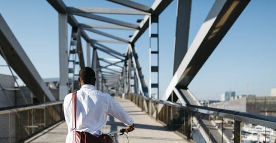 A man riding a bicycle on a bridge while pursuing new career opportunities.
