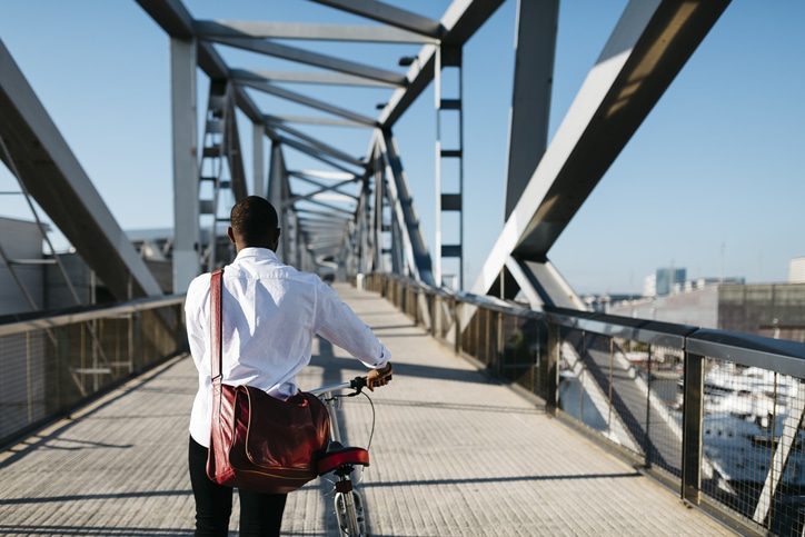 A man riding a bicycle on a bridge while pursuing new career opportunities.