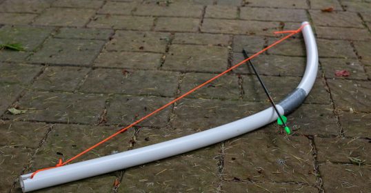A white bow with a red arrow attached to it for archery practice.