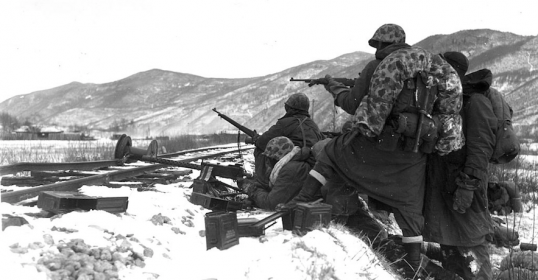 A group of soldiers standing on a snowy hill during the Korean War.