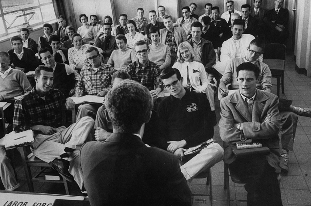 A black and white photo capturing a group of people in a classroom.