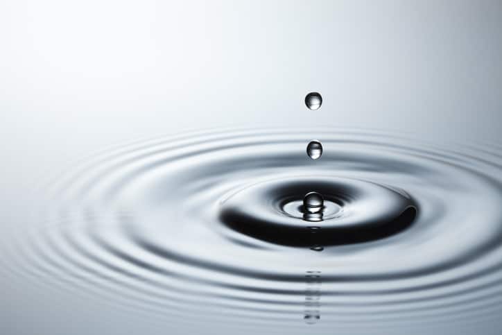 A drop of water on a white background makes a striking impact.