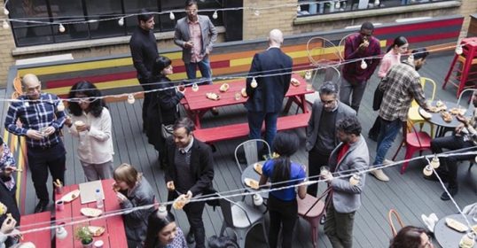 A group of people enjoying the social life on a rooftop.