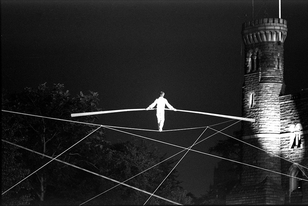 A black and white photo of a man balancing on a tight rope evokes excitement.