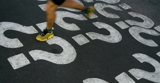A person sprinting across a street with question marks painted on it.
