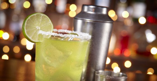 Make the perfect lime margarita on a wooden table.
