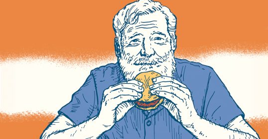Ernest Hemingway, a man with a beard, enjoying his favorite hamburger.