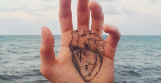 A person's hand with a heart drawn on it, symbolizing emotion.