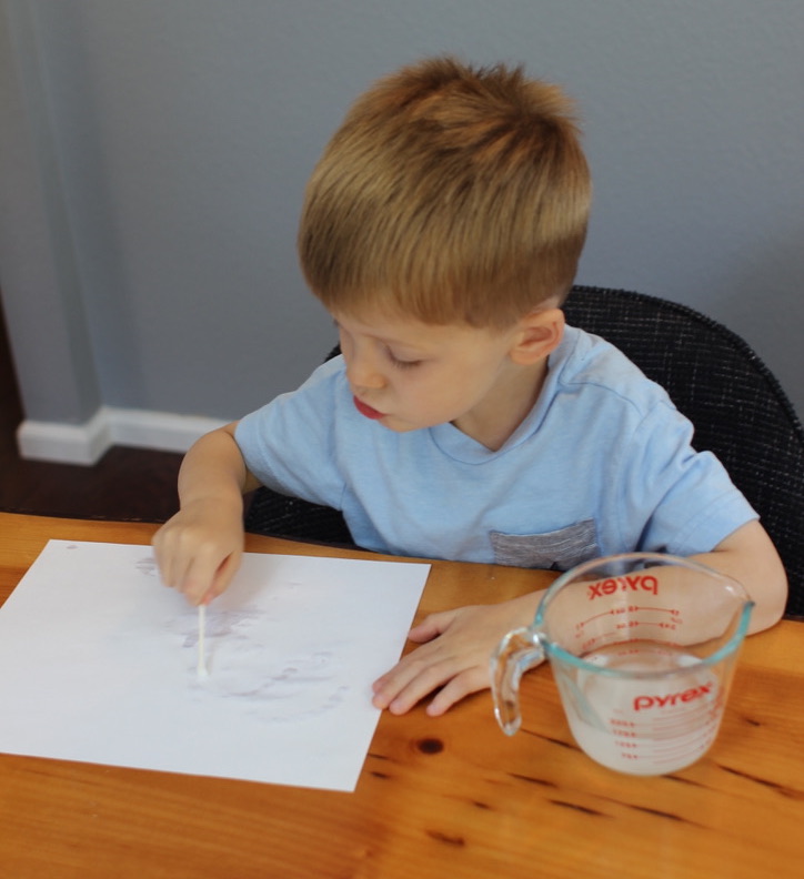 Kid is drawing with invisible ink.