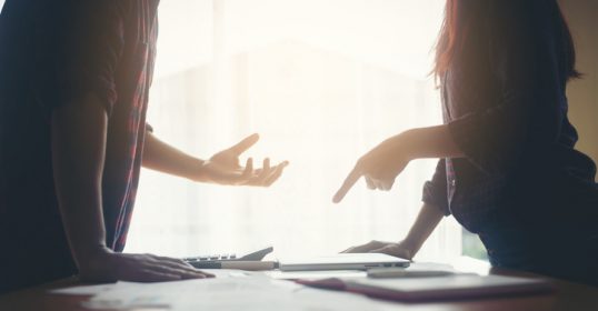 Two people engaging in a difficult conversation at a desk.