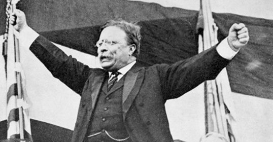 An old photo of a man with his arms raised in the air.