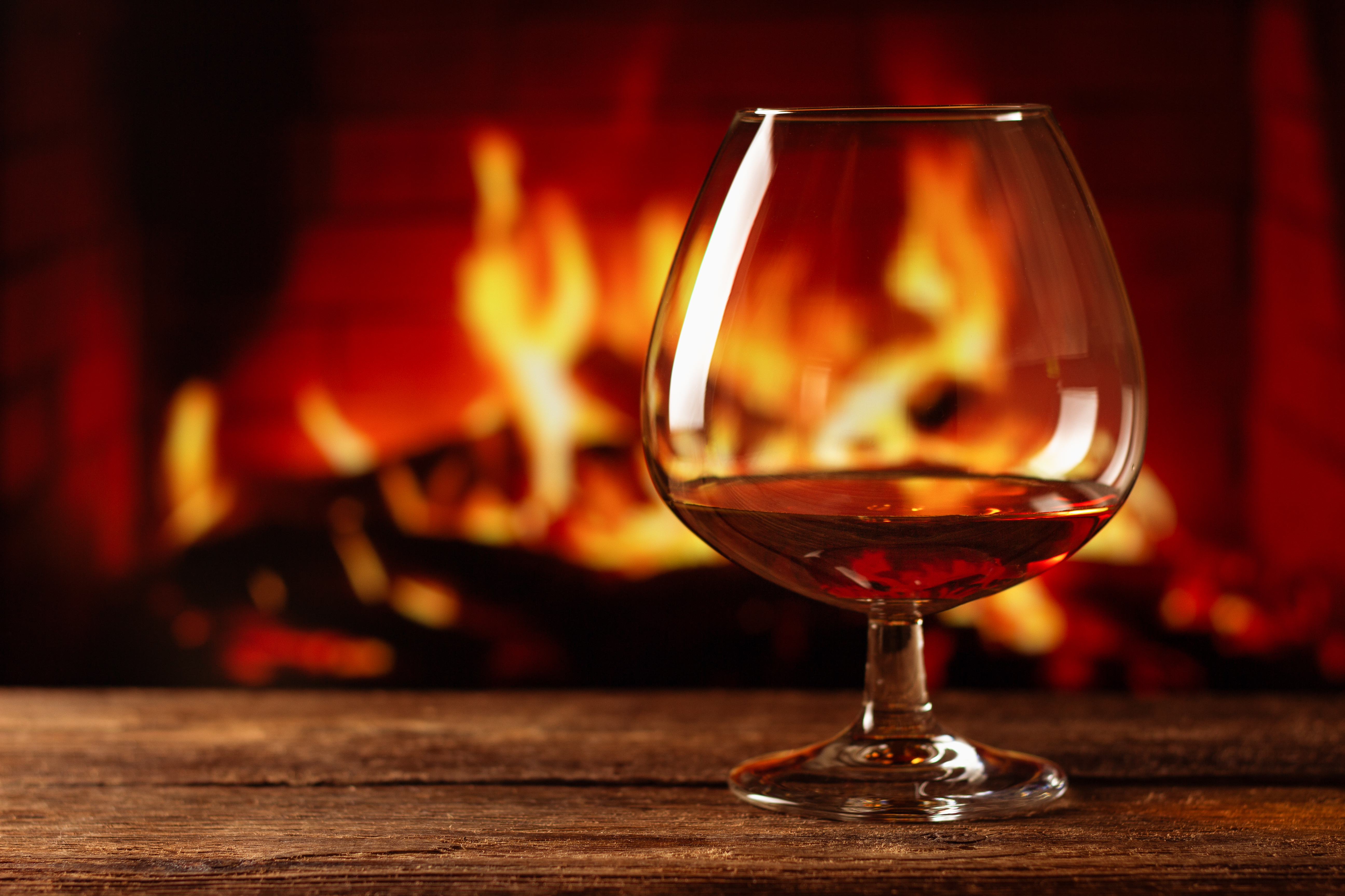 A glass of brandy in front of a fireplace.