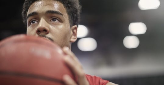 A basketball player performing, holding a ball in his hand.