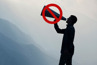 A man holding a megaphone in front of a mountain as he works towards his goals.