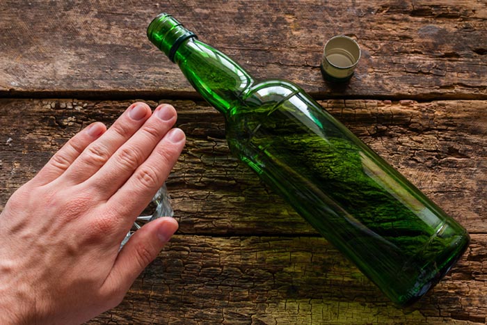 Hand on a glass and empty bottle.