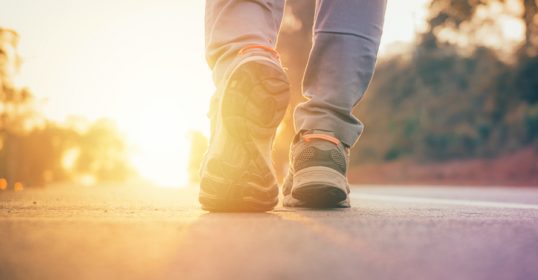 A person walking on a road at sunset, following the rules.