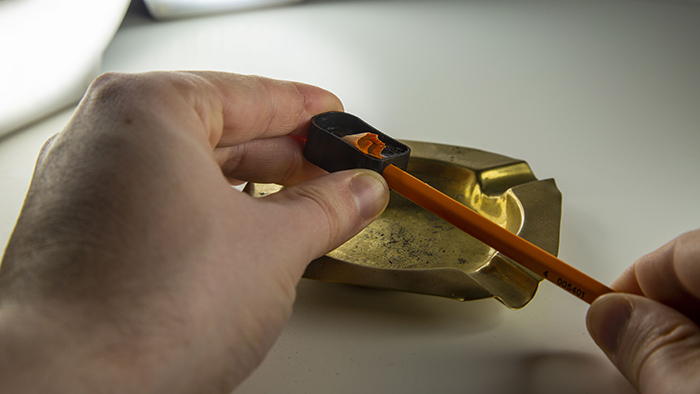 Sharping pencil with handheld sharpener.