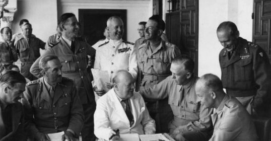 A group of military men sitting around a table, discussing wartime leaders.
