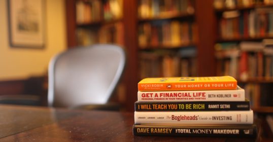 A stack of books on a wooden table for education purposes.