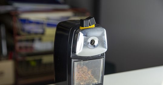 A black and yellow cigarette lighter sits on a table.