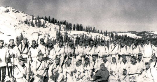 A group of skiing soldiers posing for a photo.
