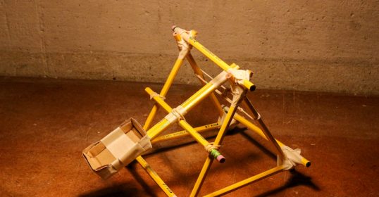 A yellow triangular Kid Craft structure on a concrete floor.