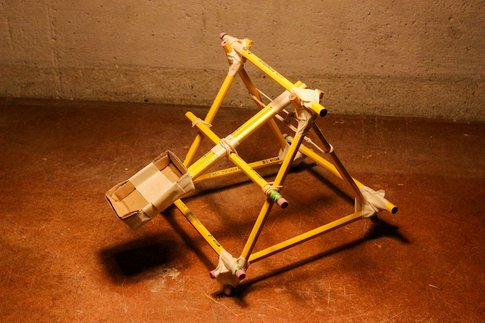 A yellow triangular Kid Craft structure on a concrete floor.