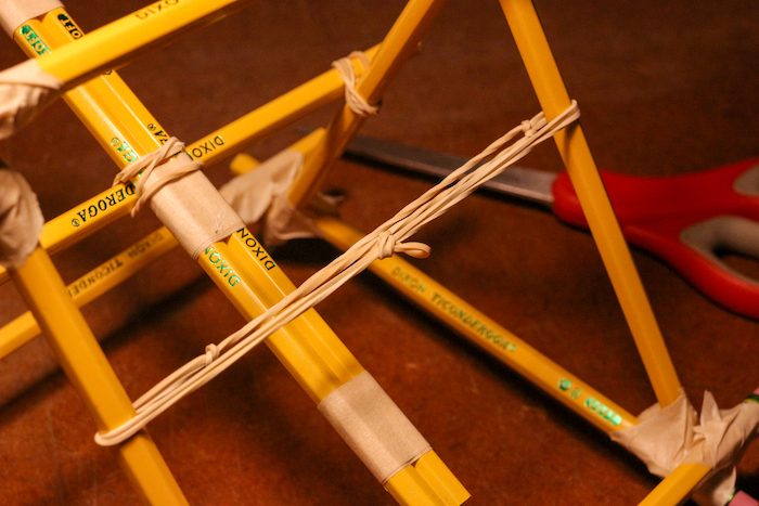 Rubber bands are stretched around the pencils.