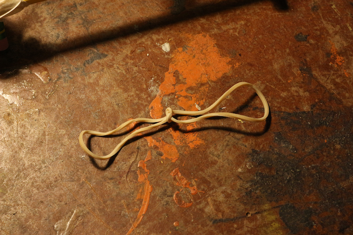 Rubber bands sharing a tiet knot with the help of hands.