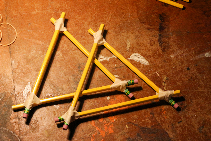 Two triangular shaped attached pencils kept on the ground.