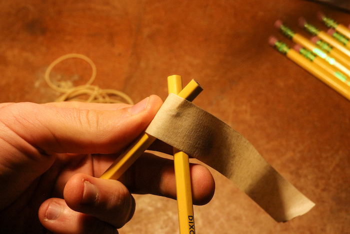 Taping one side of pencils. 