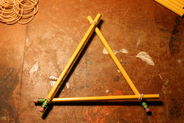 Attaching pencils with the help of rubber bands to make them triangular shaped.