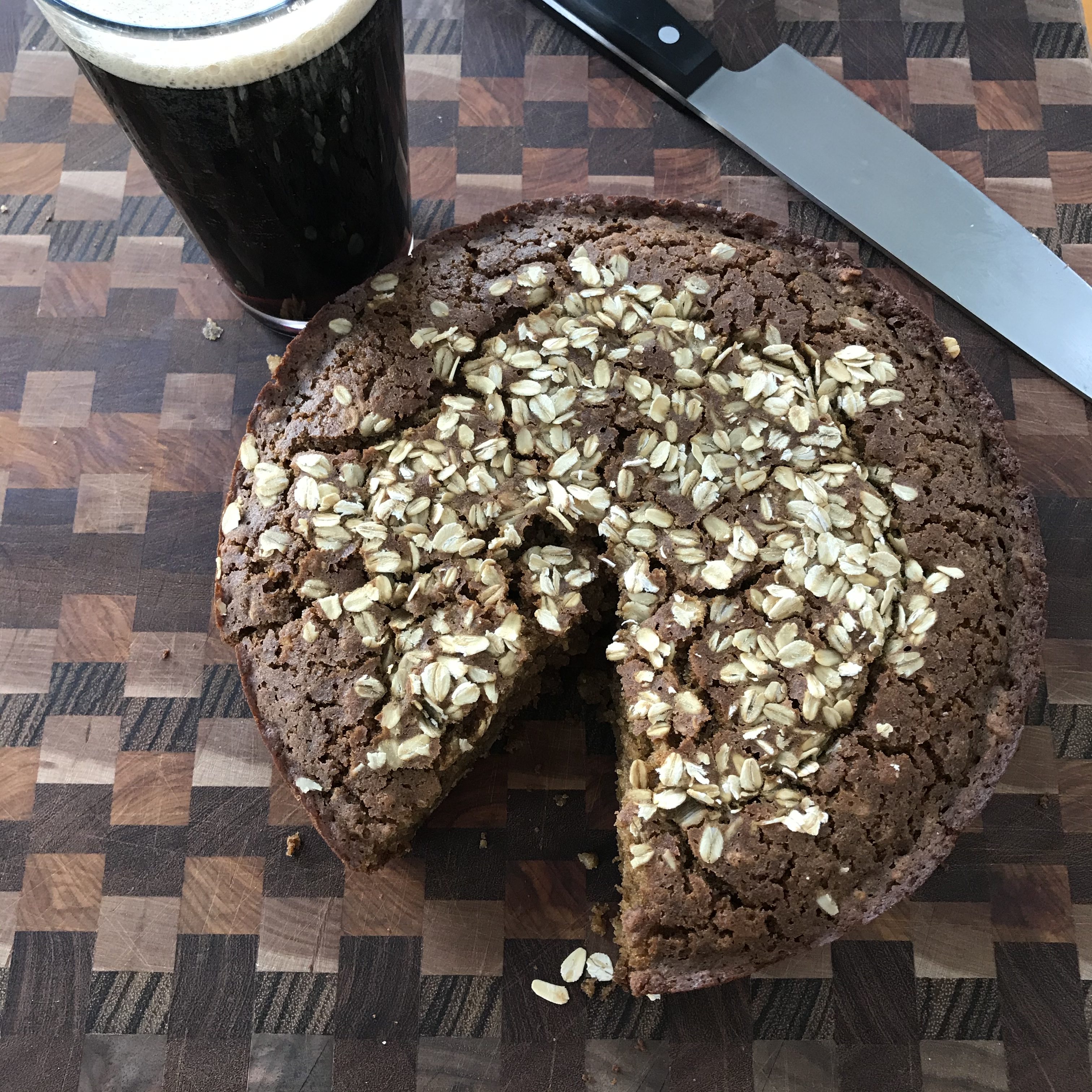 A slice of pie on a cutting board next to a glass of beer, perfect for celebrating St. Patrick's Day.