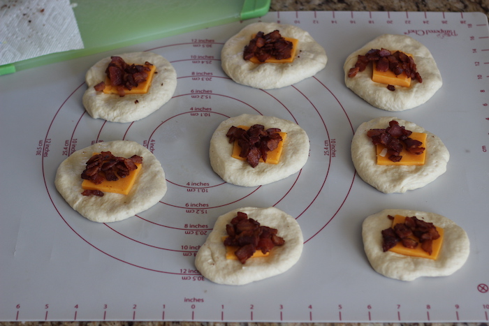 Bacon and cheese being placed on dough.