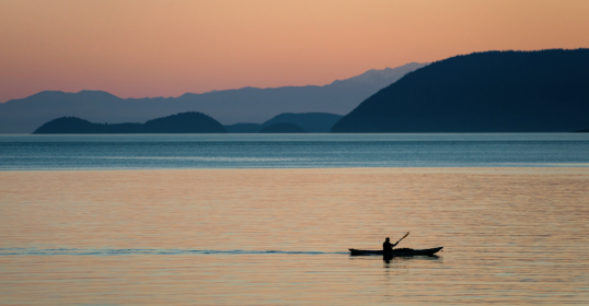 A person is journeying in a canoe on a body of water.