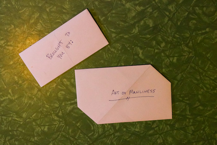 Two folded envelopes with writing on them lay on a green table.