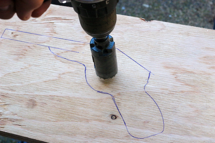 Drilling a hole in plywood having gun's image on it.
