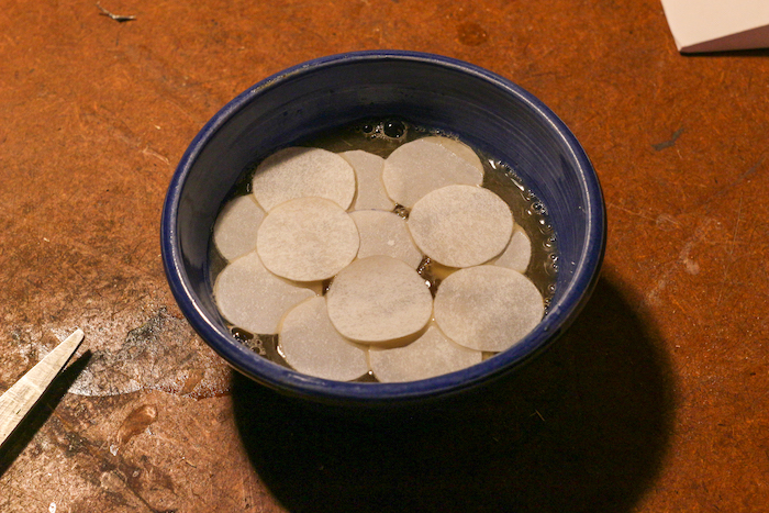 Soaking paper discs in a bowl of mixture.