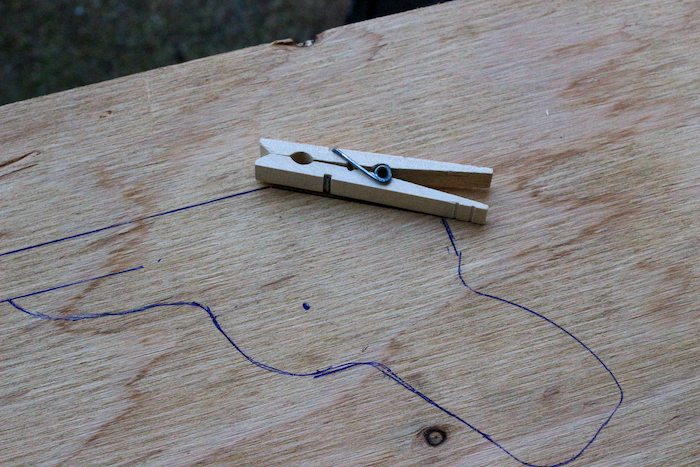 Clothespin placed along the gun drawing on plywood. 