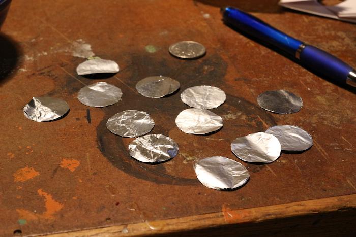 Quarter shaped foils placed on table along with pen.