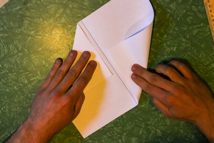 Folding adjacent corners of paper by hands.