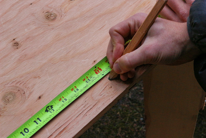 Measuring the plywood with the help of pencil and scale.