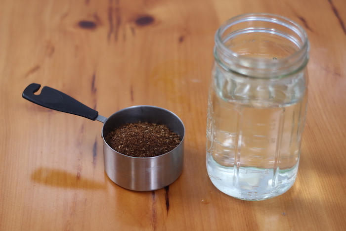 Coffee grounds in steal pan and a jar of water kept on table.