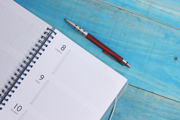 During quarantine, maintaining sanity can be a challenge. Writing in a notebook with a pen on a blue wooden table can be a helpful outlet.