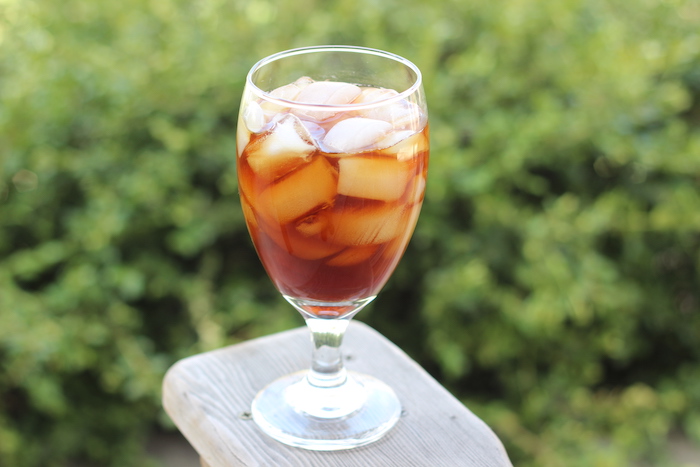 A glass of iced tea sits on a wooden table at home.