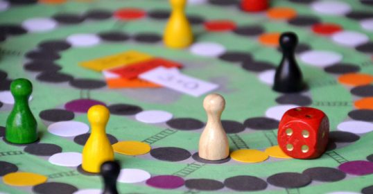 A board game with wooden pieces on a green table is a classic example of how simple pleasures in life can bring joy.
